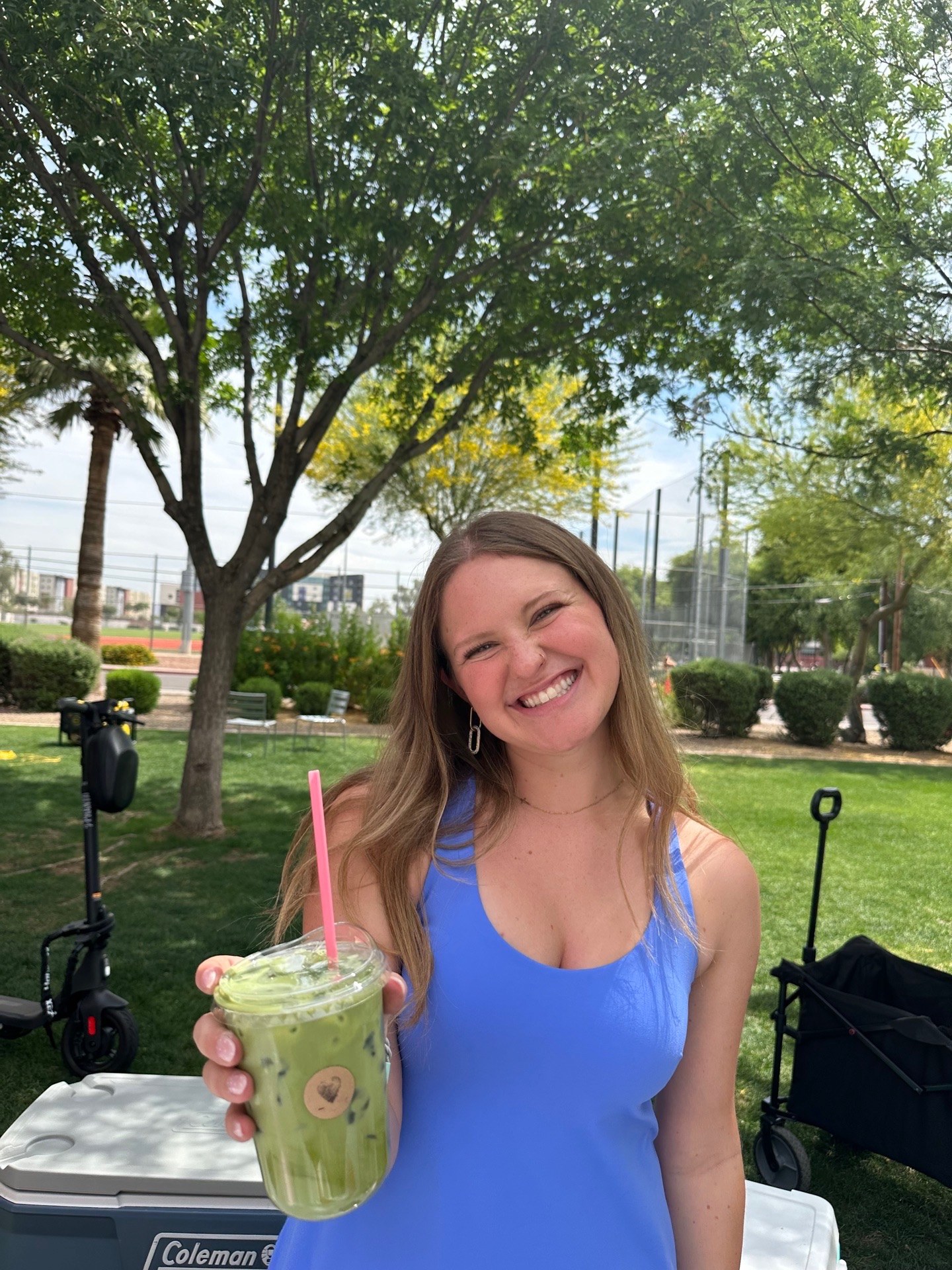 Jessie smiling at an outdoor pop-up, holding a matcha drink